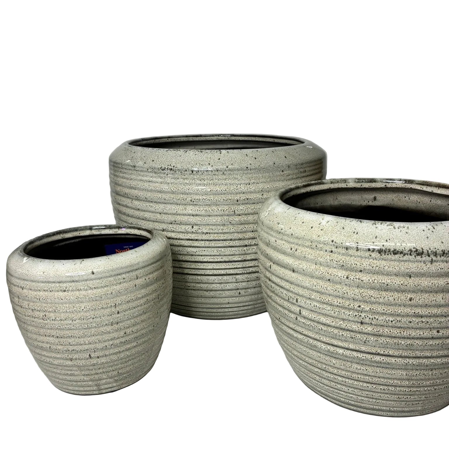 Three round ceramic planters in graduated sizes with a speckled light gray and white glaze, featuring horizontal ribbed texture and dark interior rims, displayed on a white surface against a light gray wall.